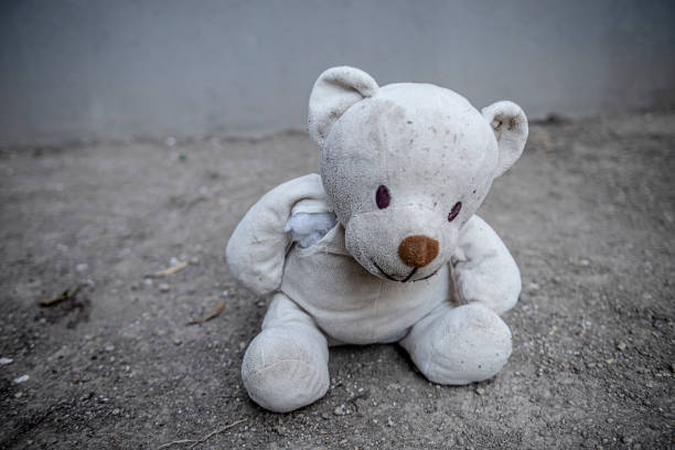 istock A damaged teddy bear on soil ground. 1287125854
