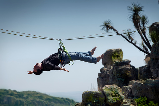young latino man, doing tightrope walking in mountains, in nature. extreme sports.