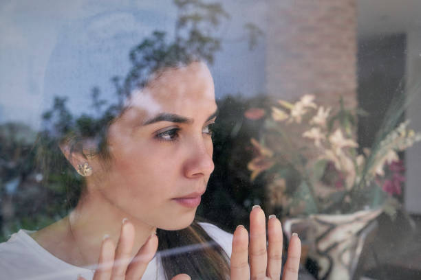 Despair Hispanic young woman looking through window