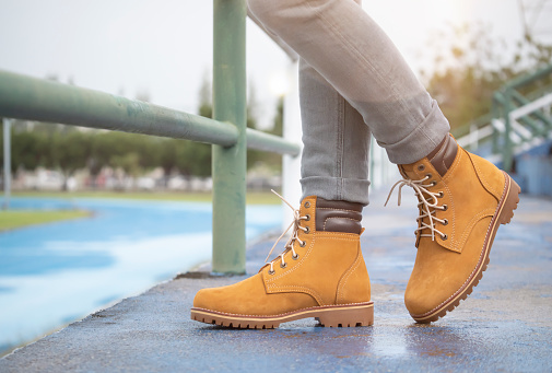 Men fashion in leather boots, Close up view on man's legs in gray jeans and yellow leather boots.