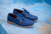Men fashion navy blue leather boat shoes on blue floor background.