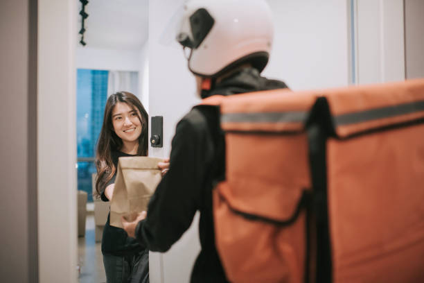 asian chinese delivery man with helmet  press door bell for grocery food delivery - entregando imagens e fotografias de stock