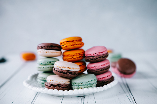 Orange pink mint and brown French macarons mixed on the plate. Makes the place look warm and yummy.