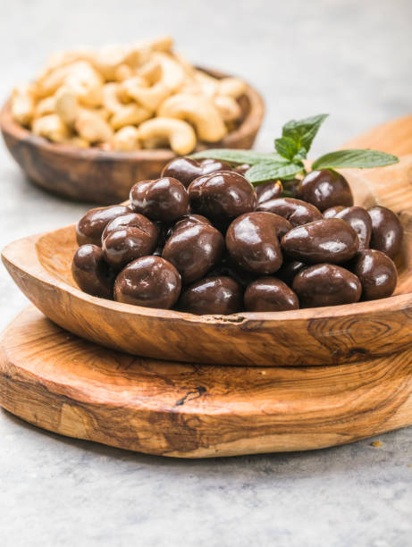 sweet cashew and chocolate covered nuts on gray stone background.