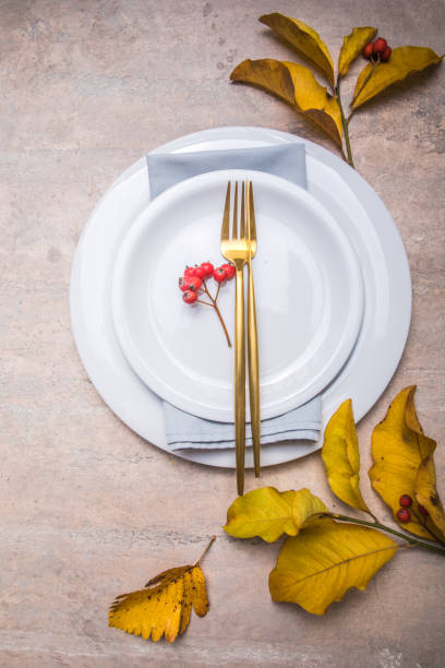 istock Thanksgiving dinner place setting, fallen leaves with plate and cutlery. 1287157372