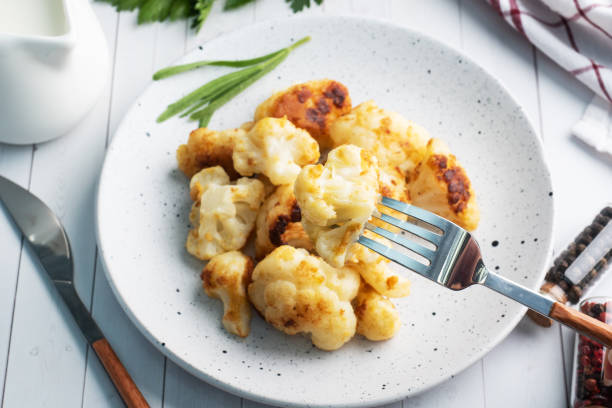 istock Fried cauliflower florets in batter on a white plate. White wooden background. 1287158170