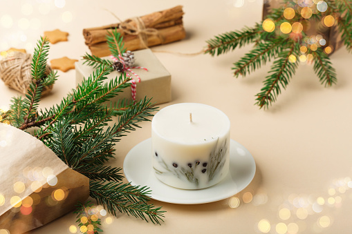 Christmas, New Year composition. Christmas zero waste eco friendly gift concept. Trendy handmade soy candle, natural decorations, gingerbread cookies on beige background,  copy space.