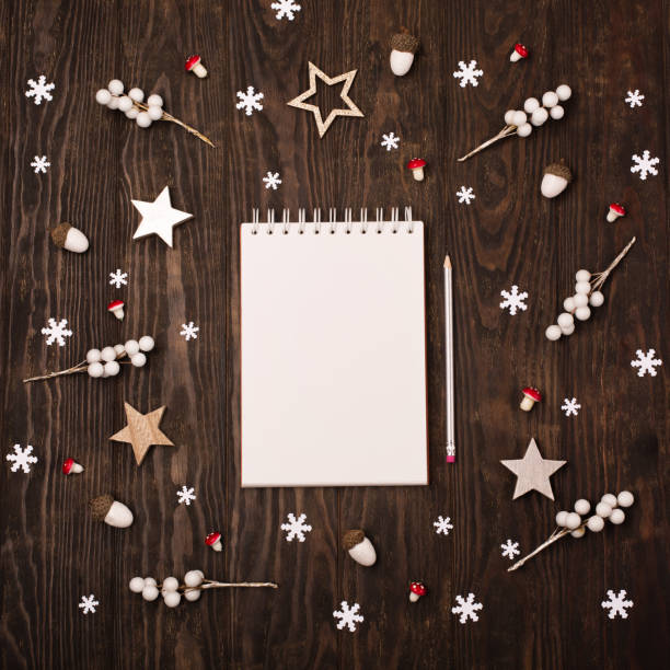 istock Empty white notebook,  Christmas decorations, snowflakes on dark wooden background. 1287160000