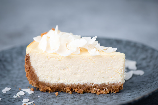 Slice of raw vegan coconut cheesecake on a plate. Coconut cashew cheesecake