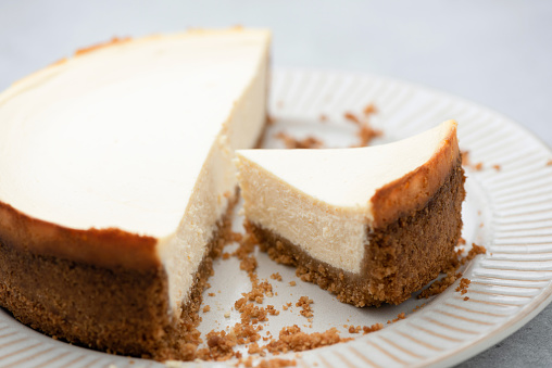 Plain new york cheesecake with slice cut out on a plate, closeup view. Tasty cheesecake