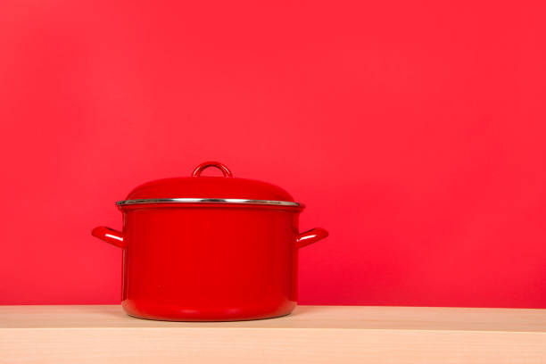 Large red cooking pan on a red background and a wooden table
