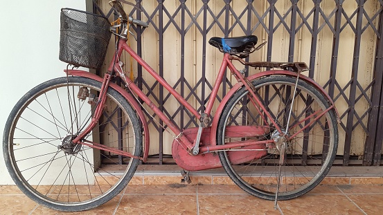 An old red bicycle parked next to the house.