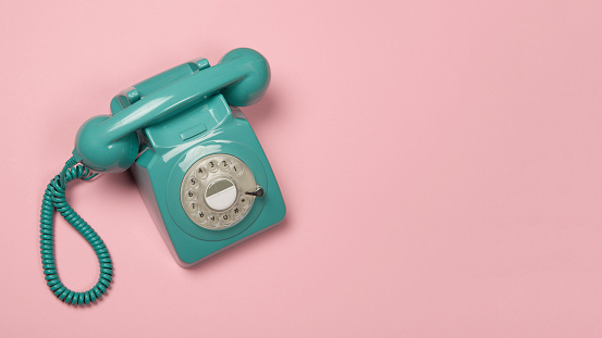 Blue vintage phone on a pink background with copy space