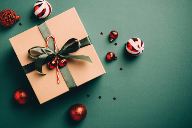 regalo di natale vintage e palline rosse su sfondo verde scuro. scatola regalo e decorazioni in stile retrò di natale. lay piatto, vista dall'alto. - regalo di natale foto e immagini stock