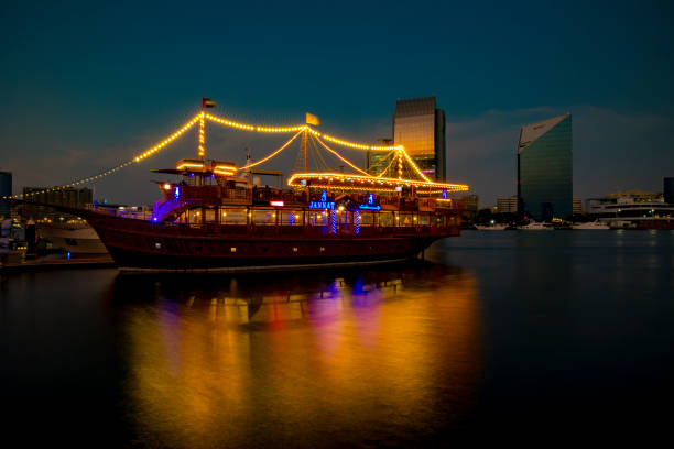 vista do riacho dubai em old dubai na área de al seef. cruzeiro de dhow lindamente iluminado ancorado com um reflexo impressionante sobre a água. - dubai skyscraper architecture united arab emirates - fotografias e filmes do acervo