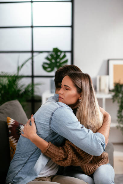 Girlfriend comforting her sad boyfriend. Young man having a problem. Girlfriend comforting her sad boyfriend. mercy hug stock pictures, royalty-free photos & images