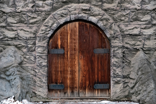 Old castle stone wall with big wooden doors. Retro wooden doors castle rock, great design for any purposes.