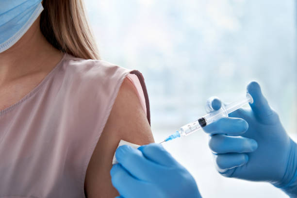 Male doctor holding syringe making covid 19 vaccination injection dose in shoulder of female patient wearing mask. Flu influenza vaccine clinical trials concept, corona virus treatment, close up view. médico masculino sosteniendo jeringa haciendo covid 19 dosis de inyección de vacunación en el hombro de la paciente mujer que lleva máscara. concepto de ensayos clínicos de la vacuna contra la gripe gripe gripe, tratamiento del virus corona, visión d
