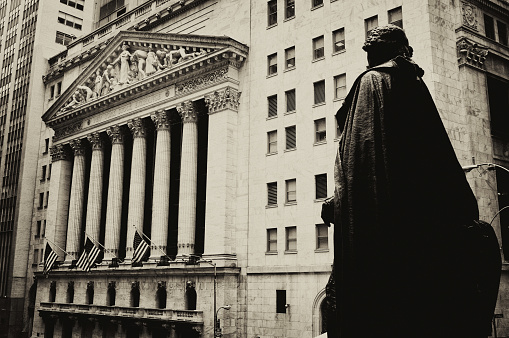 Wall Street, Manhattan Financial District, NYC, USA - May/16/2011: front view of The New York Stock Exchange building on Wall Street and George Washington statue in the foreground. Sepia toned.
