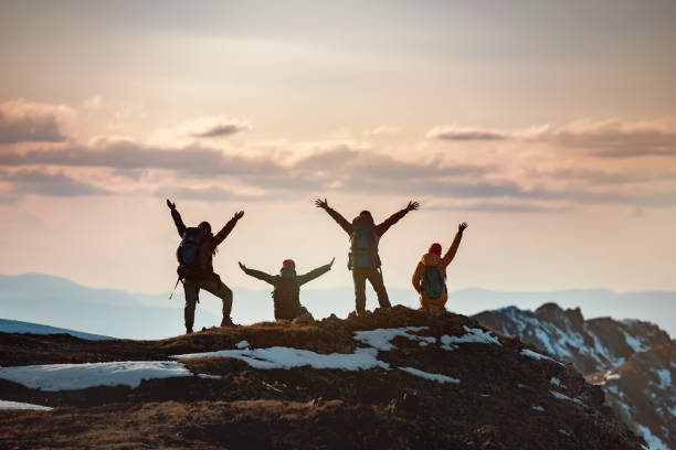 Group of hikers with raised arms at mountain top stock photo