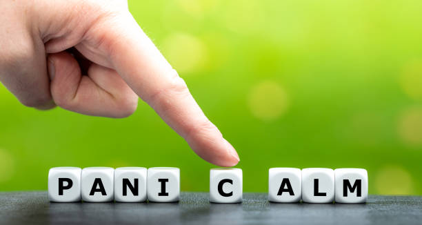 Hand moves dice and changes the word panic to calm. stock photo
