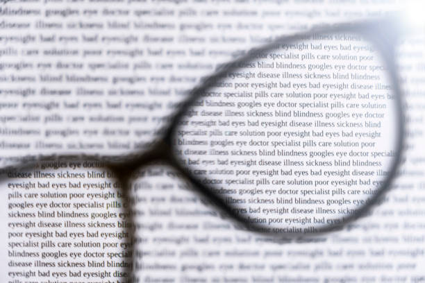 istock Unfocused black eyeglasses with view of sharp text through lenses. Bad eyesight concept. Eyecare concept. Reading concept. Selective focus. 1287180096