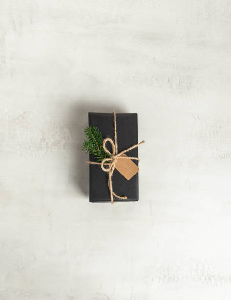 istock Wrapped gift black paper with fir tree branch and tag. 1287181883