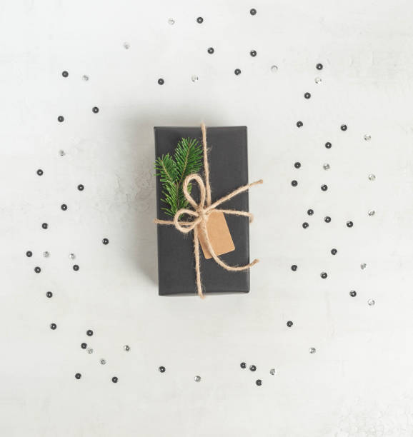 istock Wrapped gift black paper with fir tree branch and tag. 1287181892