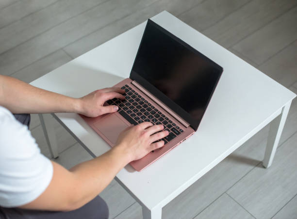 istock Man sits at a table and works at a laptop. 1287184638