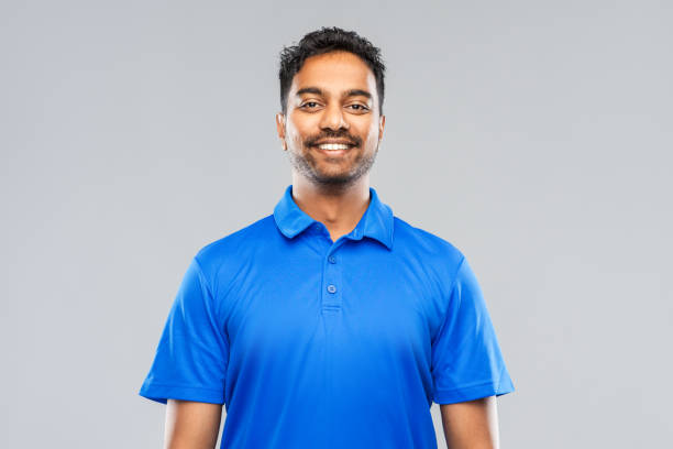homem indiano em camisa polo azul sobre fundo cinza - blue polo shirt - fotografias e filmes do acervo