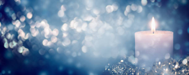 beautiful burning candlelight on abstract blurred background, shiny christmas lights at blue night, advertising space on xmas concept