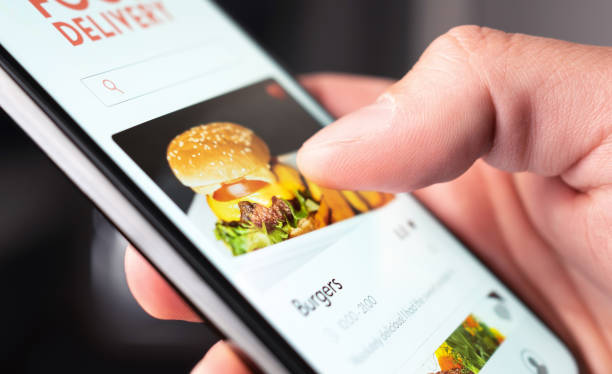 food delivery app order with phone. online mobile service for take away burger and pizza. hungry man reading restaurant menu, website and reviews with smartphone. - food imagens e fotografias de stock