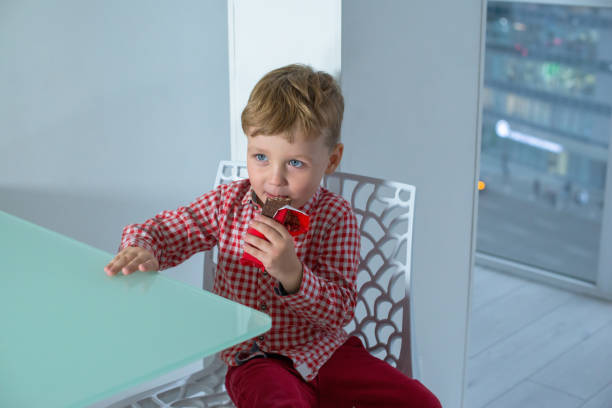 istock Boy eating chocolate bar in the kitchen. 1287188341