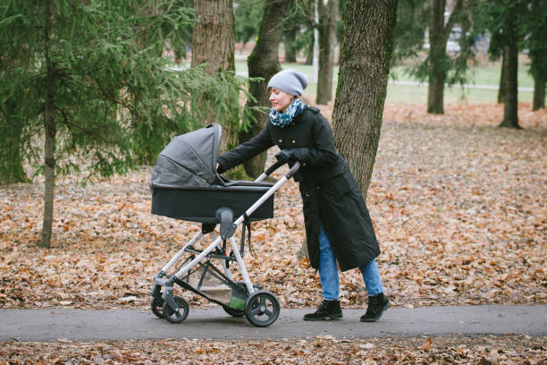 Walking with newborn baby Young mother with a stroller walking in autumn park baby stroller winter stock pictures, royalty-free photos & images