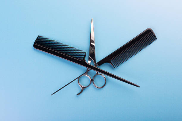 Mockup wooden frame flat lay of professional hair cutting shears, gold round hair brushes for styling, comb for separating hair and section hair clips template on orange. Hairdresser salon equipment