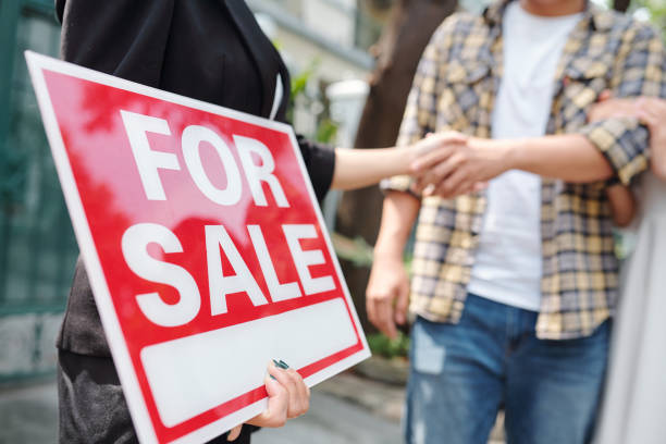 Estate agent greeting customer Real estate agent holding for sale sign and shaking hand of customer for sale sign photos stock pictures, royalty-free photos & images
