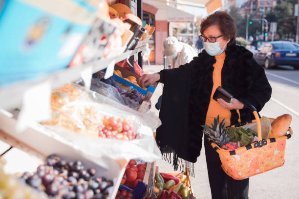 donna anziana che indossa la maschera facciale e fa shopping - senior adult aging process supermarket shopping foto e immagini stock