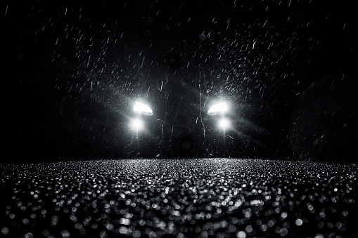 glowing car headlights at night in the rain