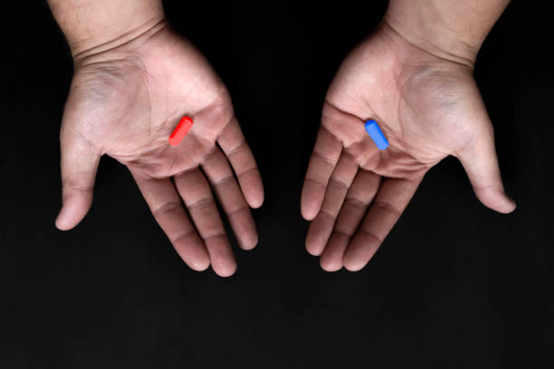 istock Red and blue pills on hand on black background. Red pill blue pill concept. 1287191996