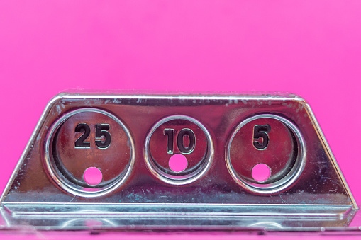 a public phone coin slots on pink background wall