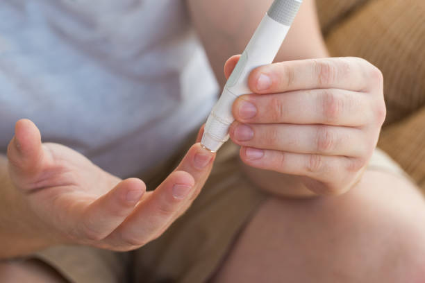 istock Man taking a blood sample with a lancet handle outside against the backdrop of greenery. Diabetes, health care, insulin concept 1287192205