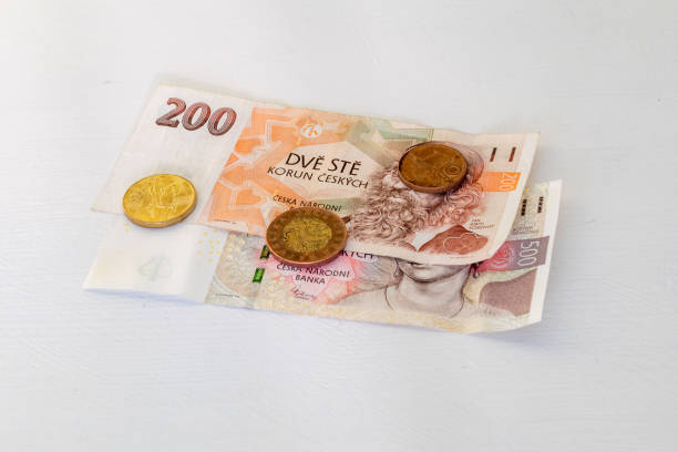 Czech koruna banknotes and coins on white table.