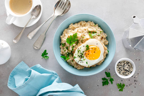 Savoury oatmeal with fried eggs sunny side up for breakfast Savoury oatmeal with fried eggs sunny side up for breakfast savory food stock pictures, royalty-free photos & images