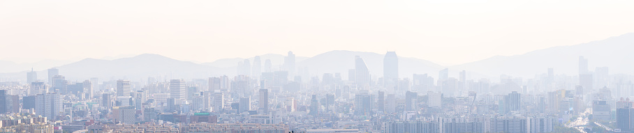 Aerial panorama over the Han River to the skyscrapers of Gangnam and crowded cityscape of central Seoul peering through the mist of early morning, Korea.
