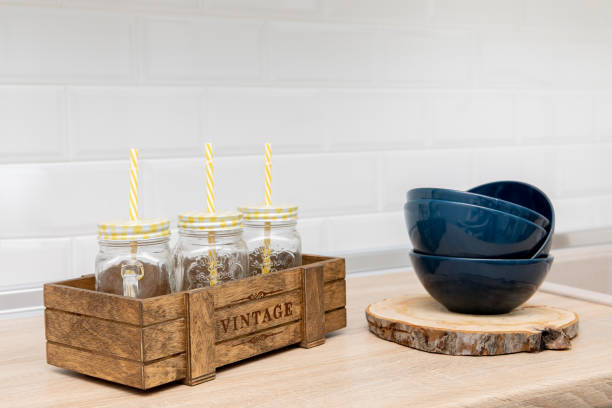 A wooden box is filled with empty glass jars against white background, all prepared for recycling. This setup showcases a sustainable lifestyle and responsible waste management.