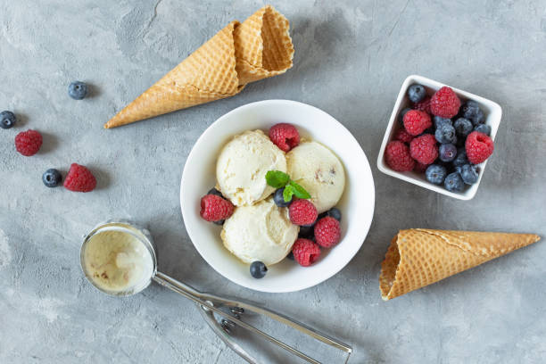 istock Vanilla ice cream scoops with raspberry and blueberry in a bowl top view on grey background. 1287197803