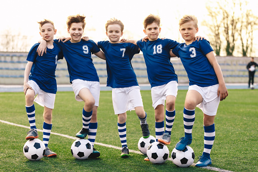 Sporty School Boys en equipo de fútbol. Grupo de niños en ropa deportiva de jersey de fútbol de pie con pelotas en el campo de césped. Niños sonrientes felices en el equipo deportivo photo