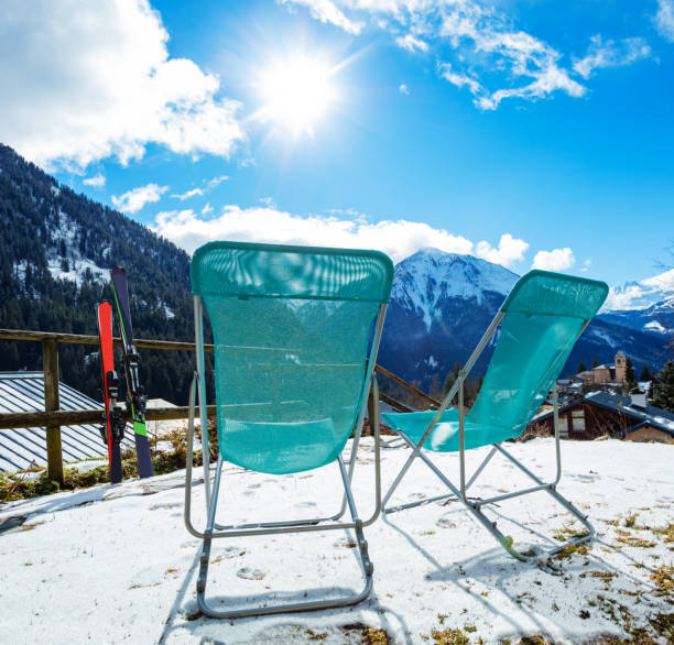 Two people resting in lounges on terrace of restaurant near l'Ouliette at Val d'Isere ski area shot against direct sunlight so the whole picture is coloured orange looking like desert landscape