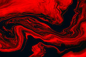 Fluid art texture. Backdrop with abstract swirling paint effect. Liquid acrylic picture that flows and splashes. Mixed paints for background or poster. Red, black and orange overflowing colors.