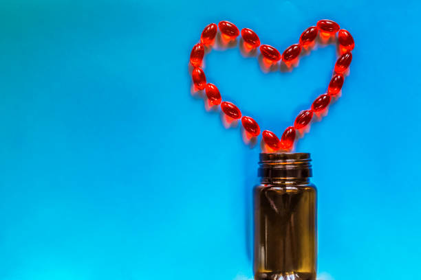 istock The red pills in heart shape on a blue background. Heart diseases problems concept. 1287201519